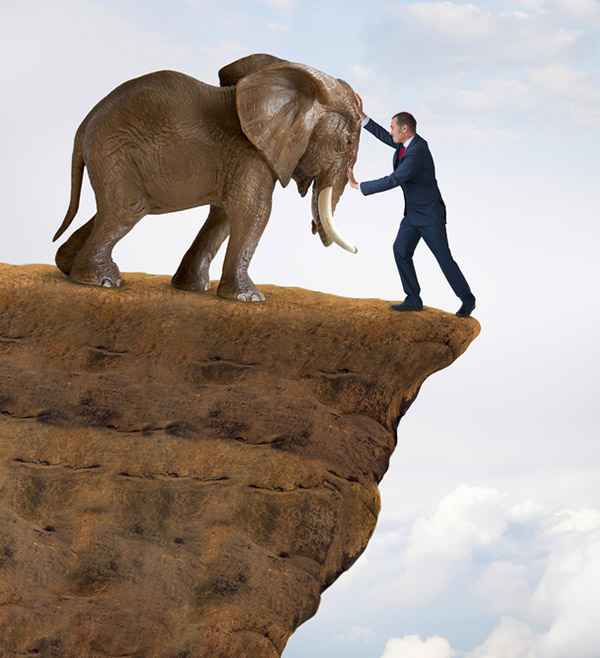 business strength concept businessman pushed to the edge of a cliff by an elephant